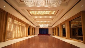 A spacious hall with a wooden floor, large windows, and a chandelier. - Hotel Amora (Rajnandgaon)