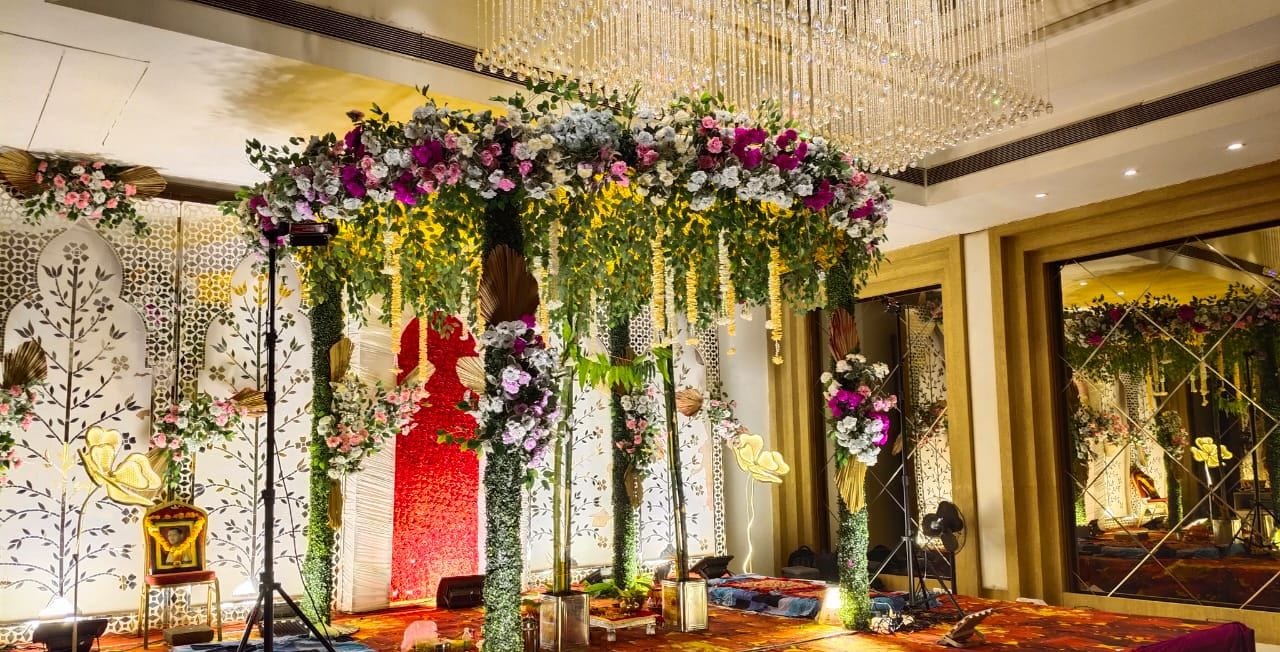 A decorated event space with floral arrangements, a stage, and a chandelier.