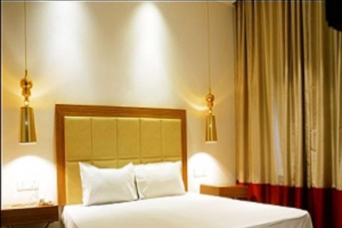 Une chambre d’hôtel avec un grand lit, deux tables de chevet et une tête de lit en bois.