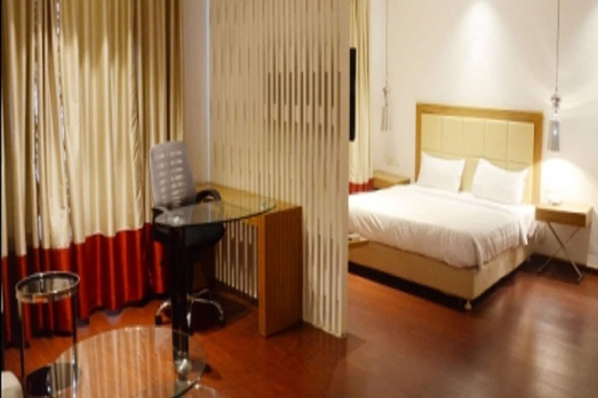 Une chambre d’hôtel avec un lit, une table de chevet et une table en verre avec une chaise.