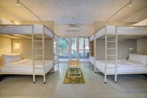 Una habitación con literas, una mesa central y vistas al exterior.