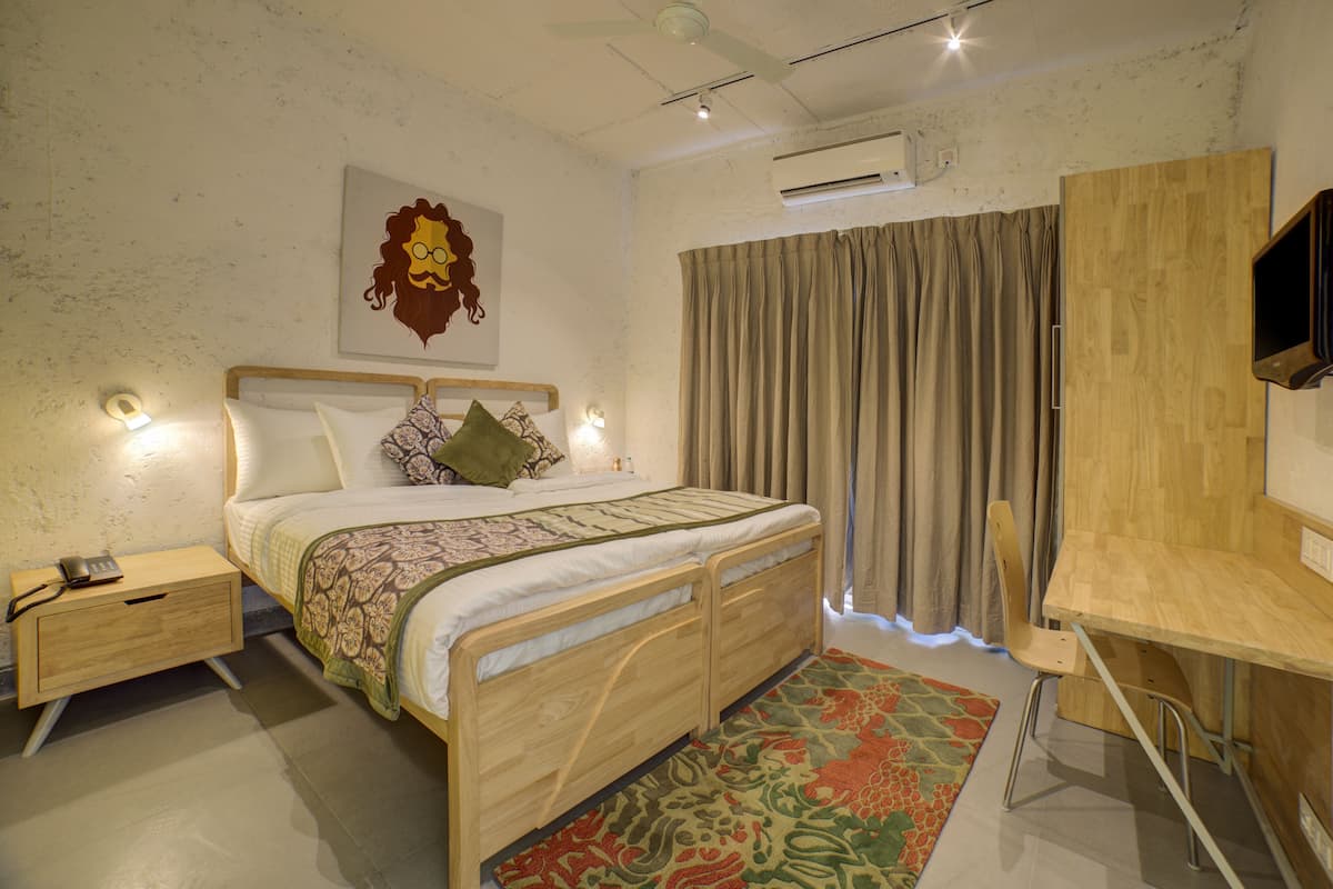 A bedroom with a bed, bedside table, and a desk with a chair.
