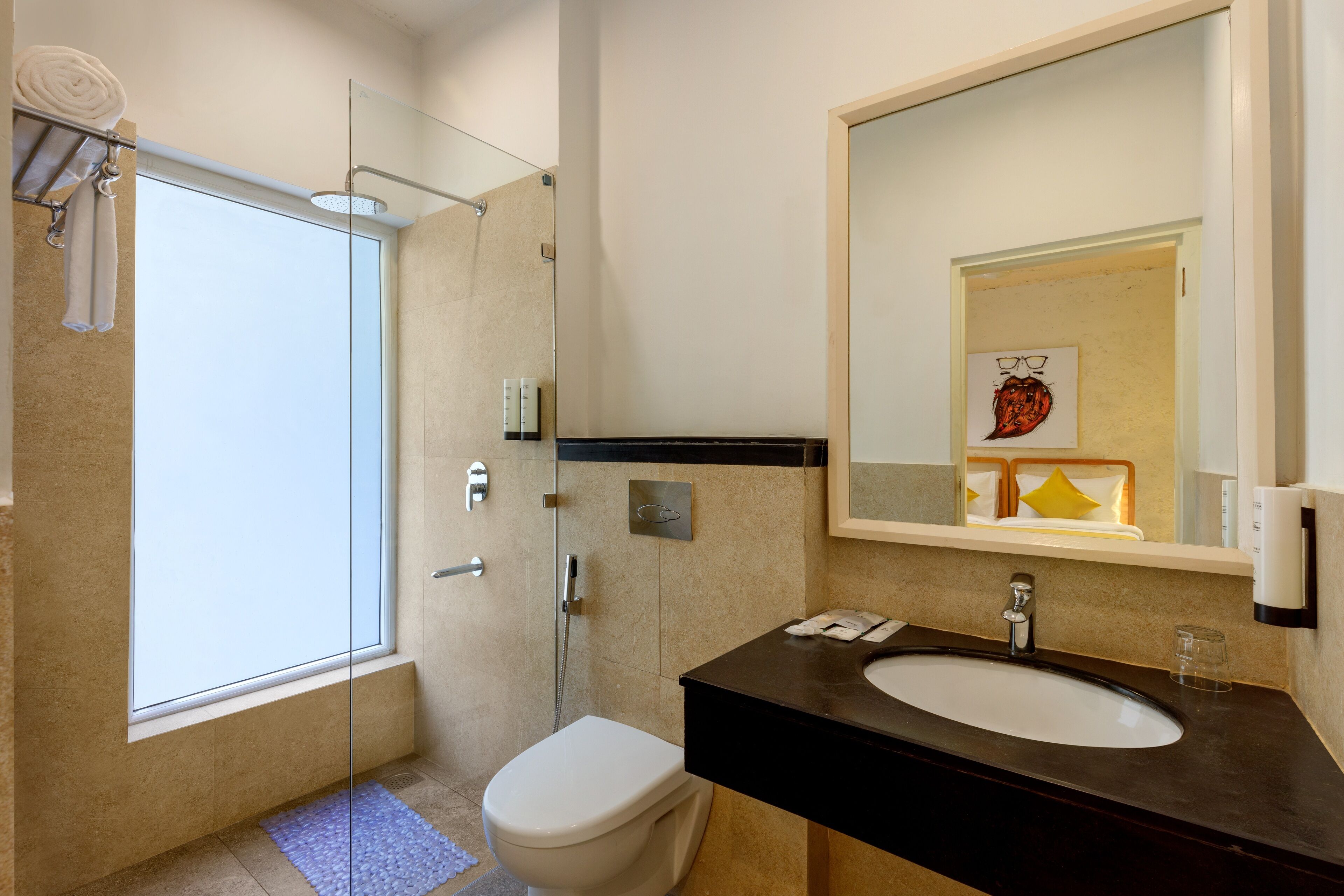 A modern bathroom with a glass shower enclosure, a white toilet, a dark sink, and a large mirror.