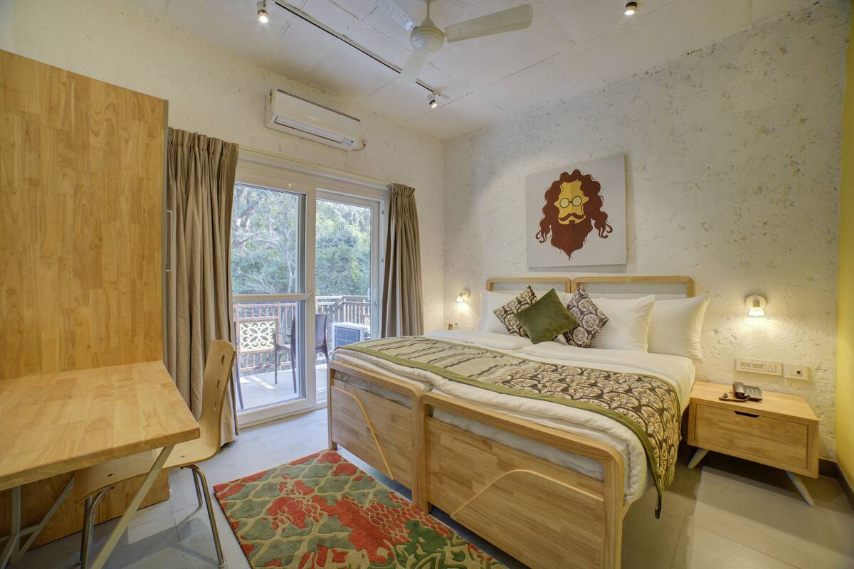 A bedroom with a wooden bed, a desk, a chair, a nightstand, and a window with curtains.