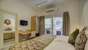 Une chambre d’hôtel équipée d’un lit, d’un bureau, d’une chaise, d’une télévision et d’une fenêtre avec des rideaux.
