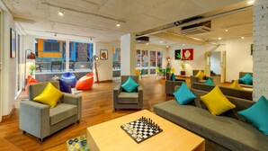 Un vaste espace de détente avec de nombreux sièges, notamment des canapés et des fauteuils, et une table d’échecs placée au centre.