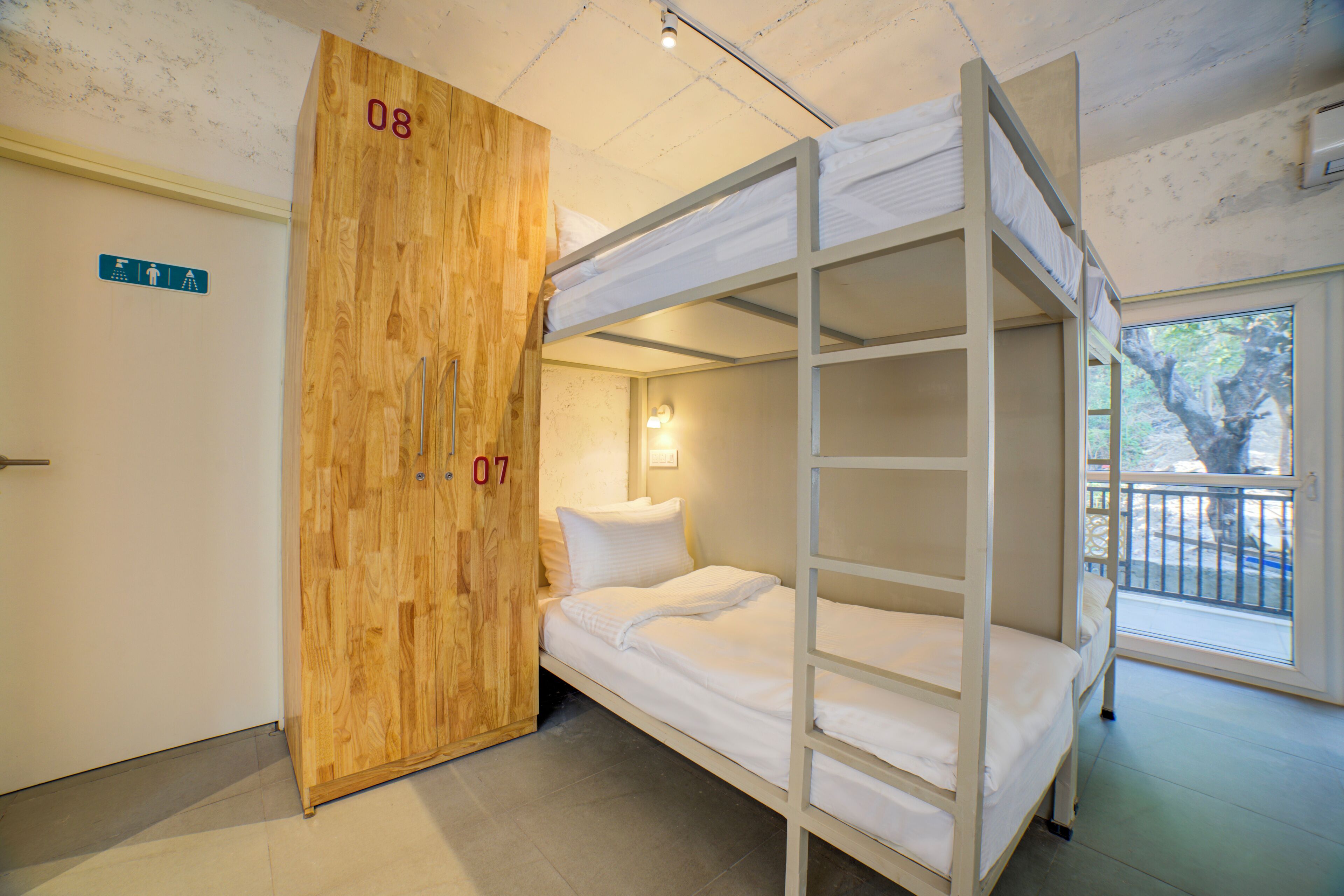 A bunk bed room with a wooden wardrobe and a window with a view.