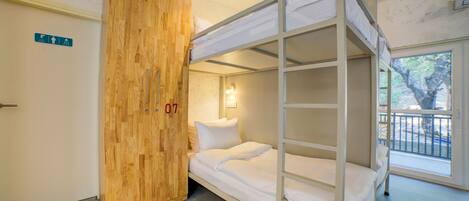 A bunk bed room with a wooden wardrobe and a window with a view.