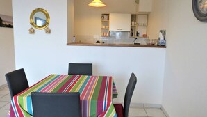 A dining area with a striped tablecloth, two chairs, a mirror, and a kitchen in the background. - Apartment with terrace, WIFI and parking in Perros-Guirec (Perros-Guirec)