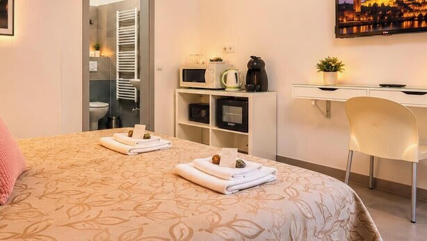 Habitación de hotel impecable con cama, mesita de noche, lámpara y escritorio con silla.