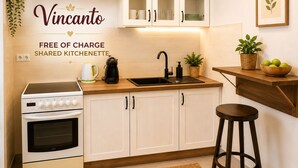 Una cocina con armarios blancos, estufa, lavamanos y un taburete de bar.