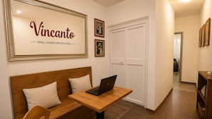 Un espacio pequeño y privado con un sofá de madera, una computadora portátil sobre una mesa y un letrero enmarcado que dice 'Vincanto'.