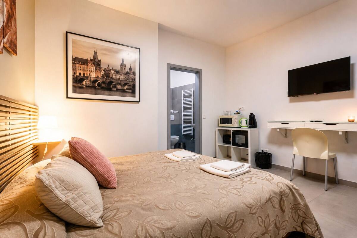 Een hotelkamer met een bed, een bureau, een televisie en een stadsgezicht op een foto.
