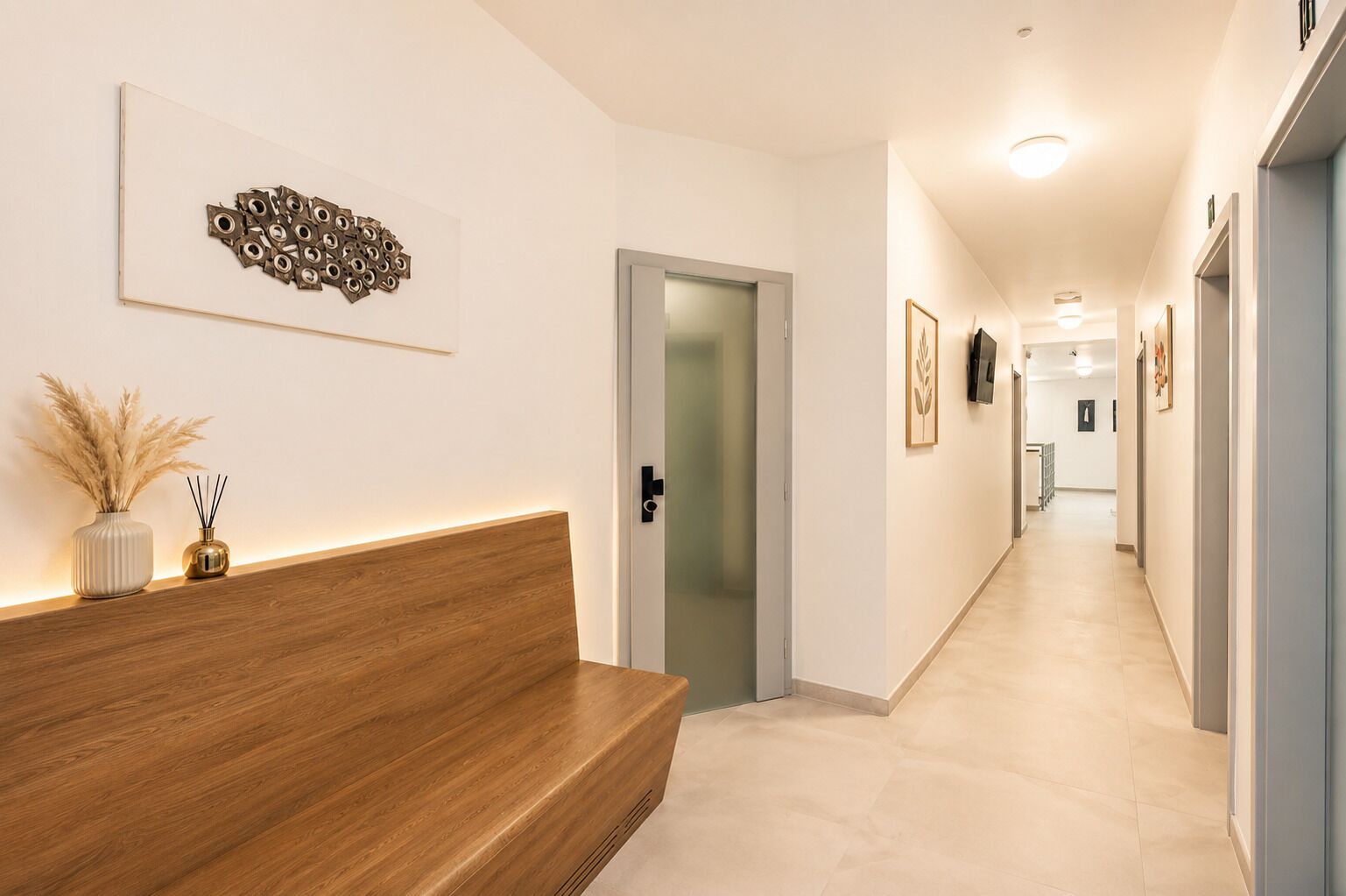 A hallway with a wooden bench, a wall-mounted decorative piece, and a door.
