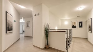 Un pasillo de hotel con obras de arte enmarcadas, una recepción y señalización direccional.