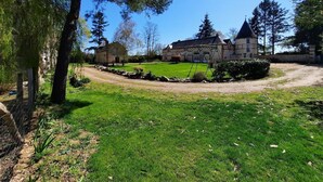 A large, historic building with a prominent tower, surrounded by a well-maintained lawn and trees. - A dream holiday in the heart of nature in a historic setting (Beaumont-Louestault)