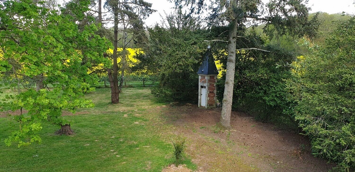 Um jardim com uma pequena torre de tijolos e uma árvore em primeiro plano.