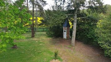 Um jardim com uma pequena torre de tijolos e uma árvore em primeiro plano.