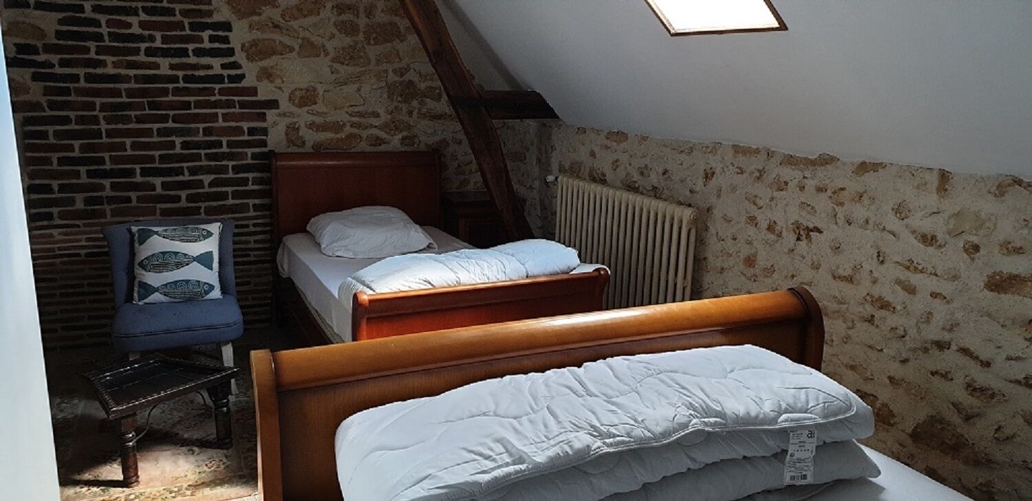 Ein kleiner, gemütlicher Raum mit schrägen Wänden, einem Holzbett, einem kleinen Stuhl und einer Heizung.