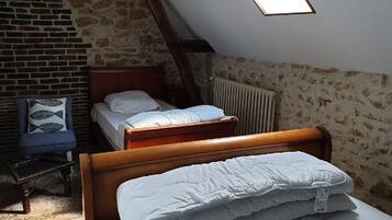 Een kleine, knusse kamer met een schuine kap, een houten bed, een kleine stoel en een radiator.