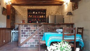 A rustic kitchen with a brick wall, wooden counter, and a table with a blue tablecloth. - A dream holiday in the heart of nature in a historic setting (Beaumont-Louestault)