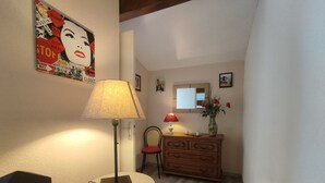Una habitación con una lámpara sobre una mesita, un aparador con espejo y un cartel en la pared.