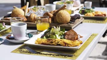 Buffet de l'esmorzar amb diferents plats, com ara ous, tocínet i pastissos, sobre una taula amb camavisc blanc.