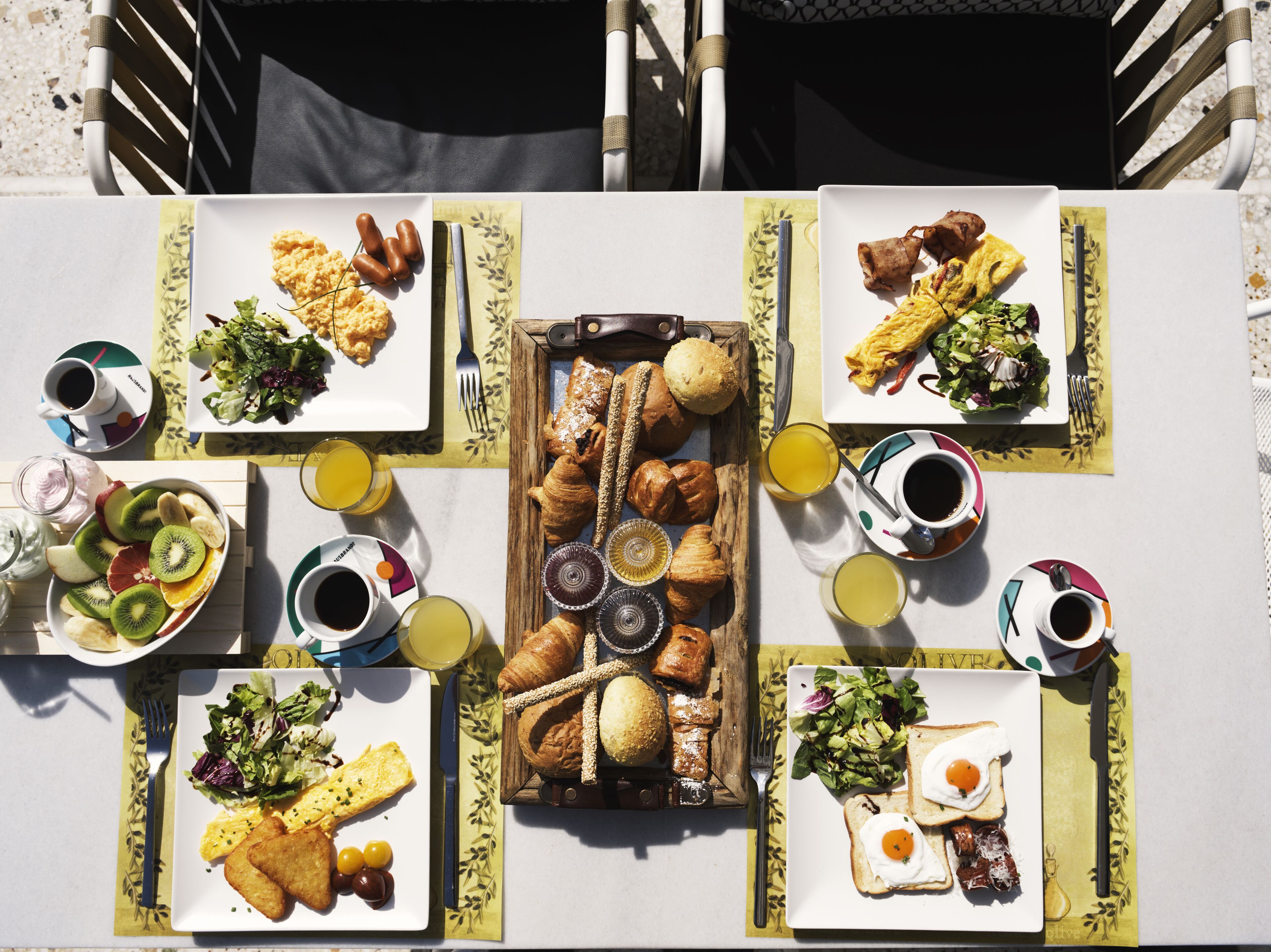 A table set with breakfast items including croissants, eggs, and fruit.