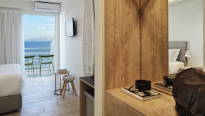 Habitación de hotel con cama, escritorio, cámara, libro y vista al mar.