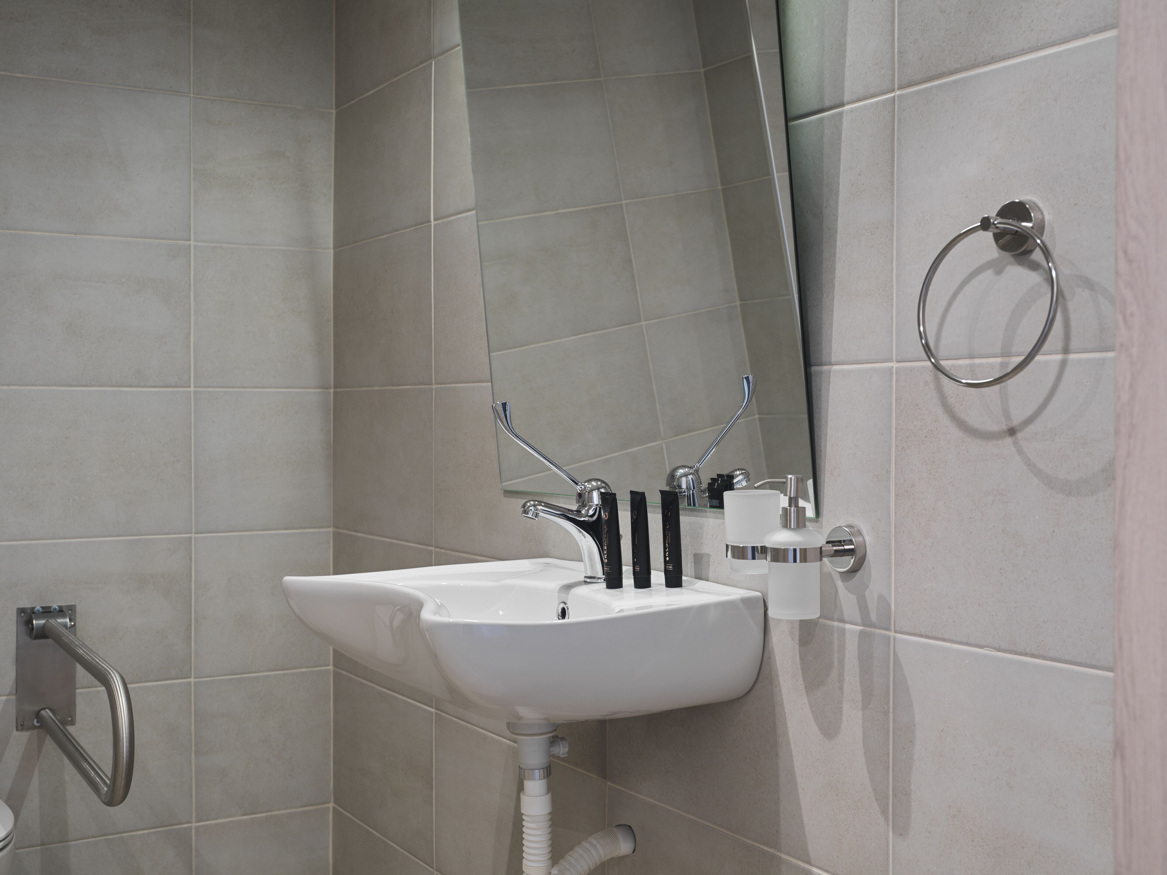 A modern bathroom with a white sink, chrome fixtures, and a large mirror.