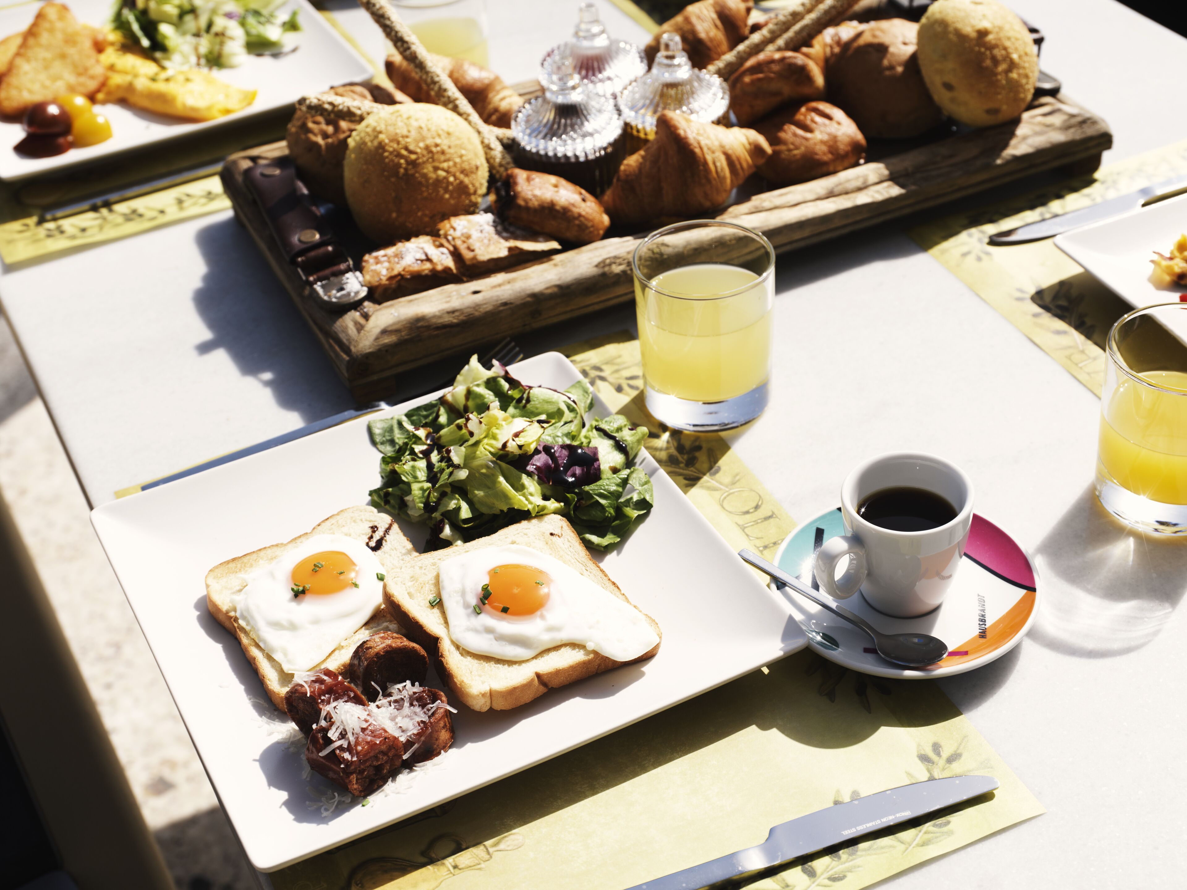 A breakfast table with croissants, toast with eggs, a salad, and beverages.