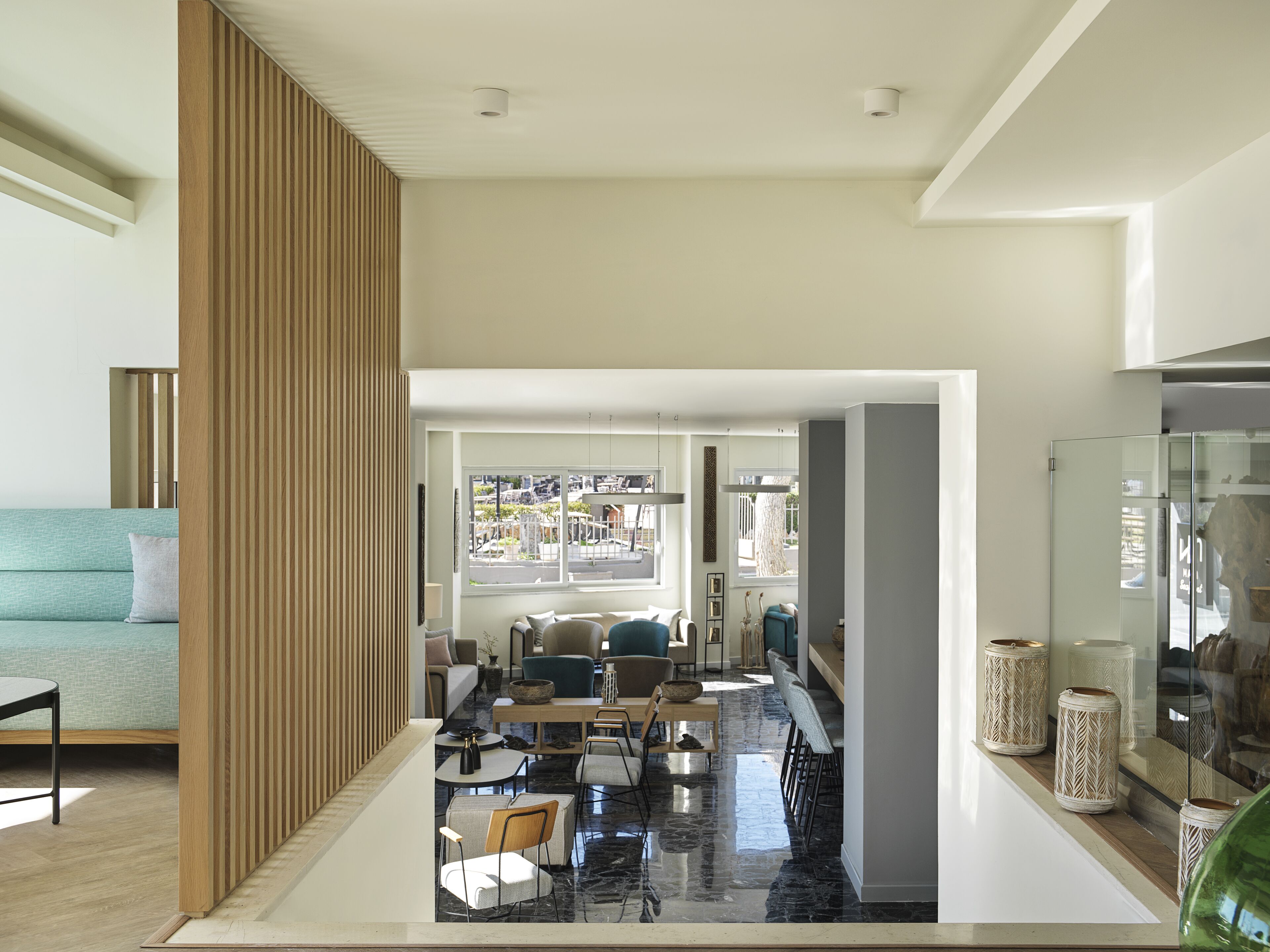 A modern living room with a sofa, chairs, a coffee table, and a dining area with a glass partition.