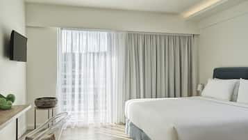 Una habitación de hotel moderna con una cama grande, un escritorio con una silla y un televisor en la pared.