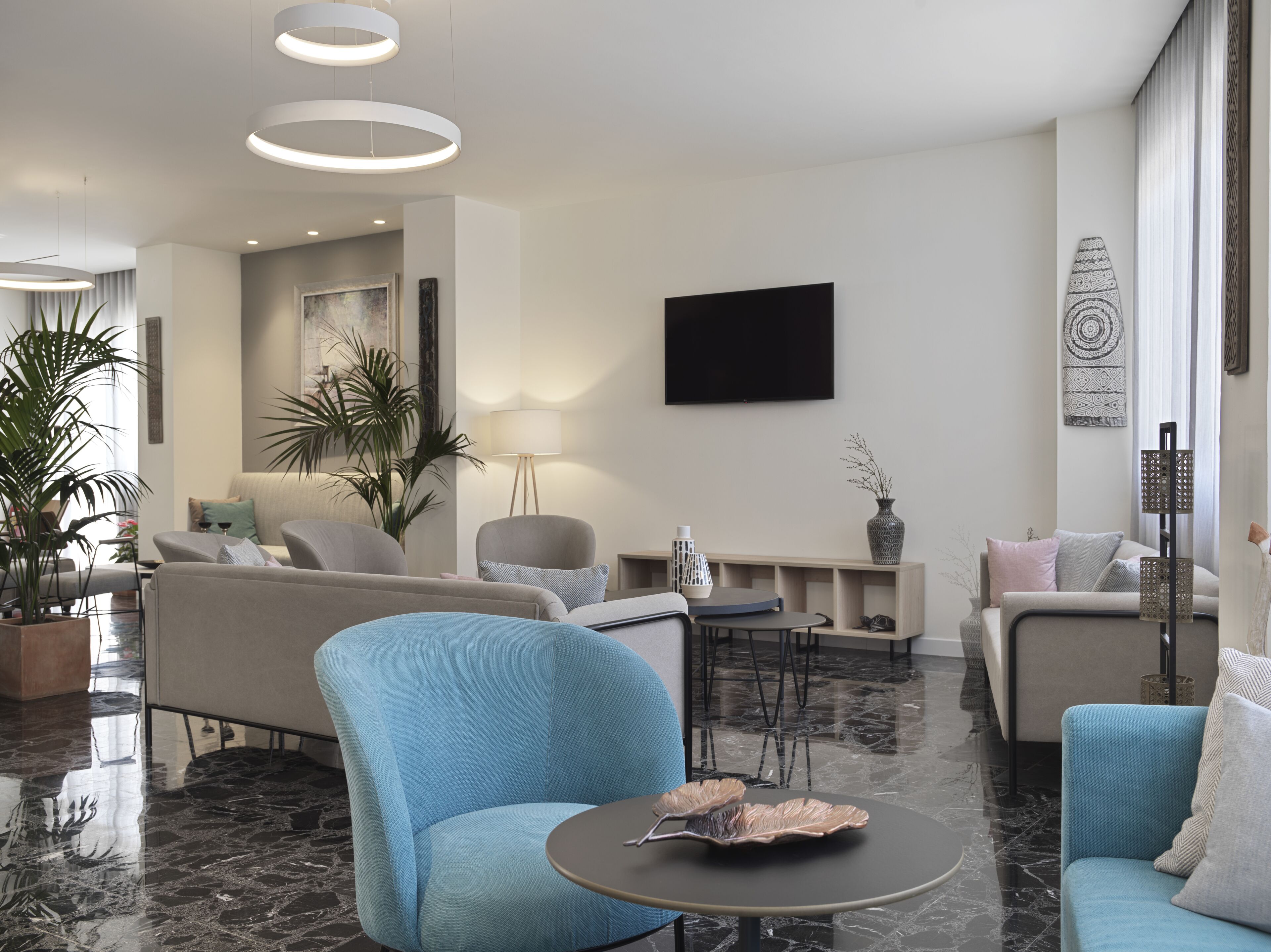 A modern living room with a sofa, armchairs, a coffee table, and a TV.