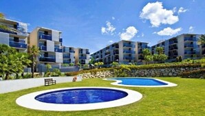 Ein moderner Apartmentkomplex mit zwei Schwimmbecken, umgeben von gepflegten Rasenflächen.