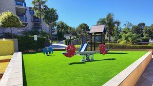 Un parque infantil con un sube y baja, un tobogán y una estructura para escalar.
