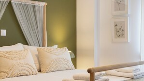Un lit bien fait, avec un cadre en bois, un mur vert et une petite table de chevet sur laquelle se trouve une lampe.