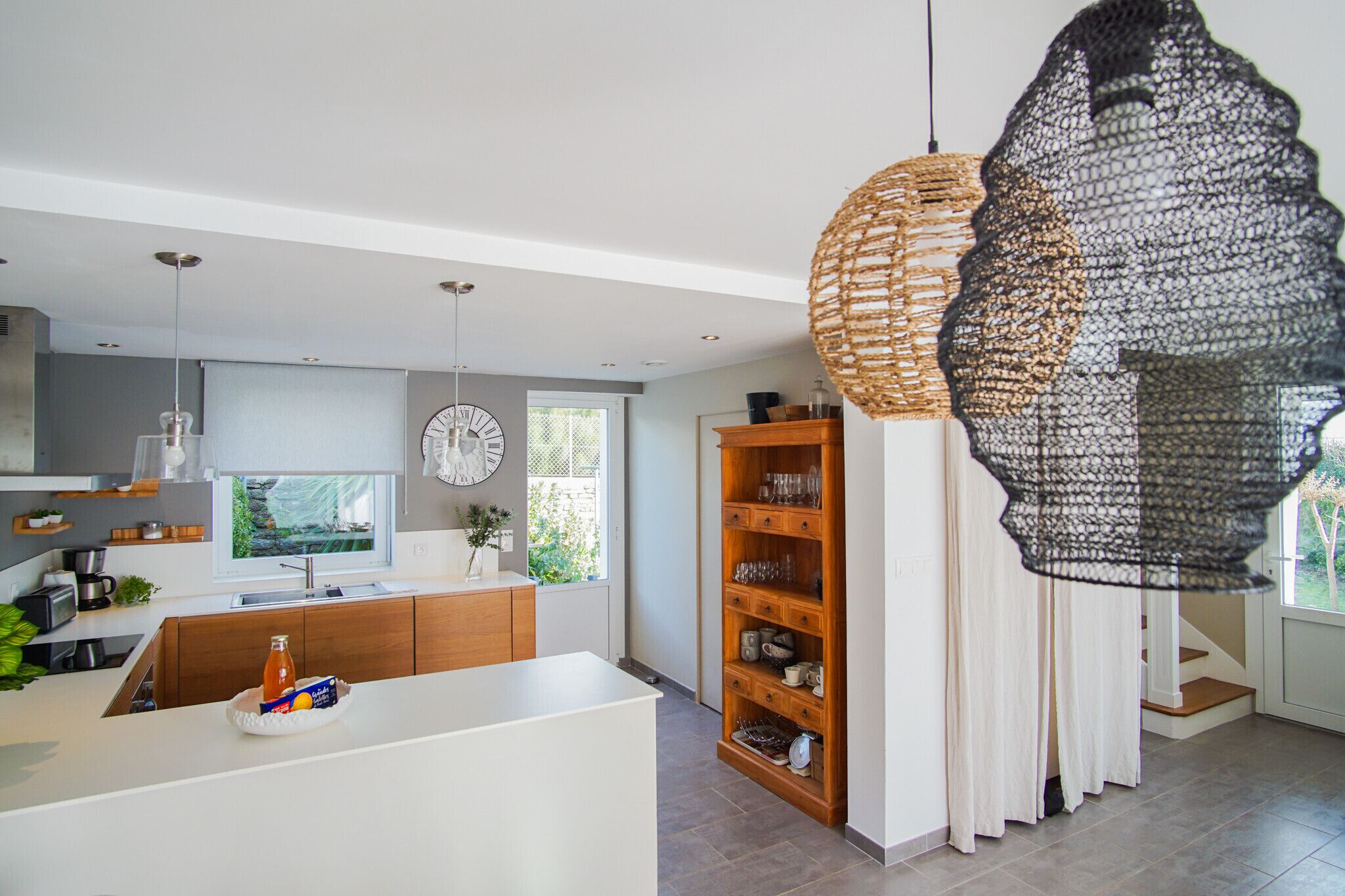 Een moderne keuken met een centraal eiland, houten keukenkastjes en hanglampen.