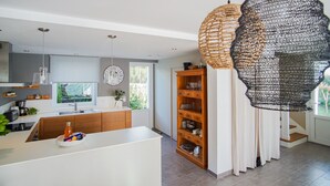 A modern kitchen with a central island, wooden cabinets, and pendant lighting.