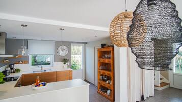 Een moderne keuken met een centraal eiland, houten keukenkastjes en hanglampen.