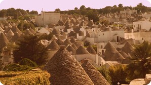 A village with numerous conical-roofed buildings, likely traditional houses, surrounded by greenery.