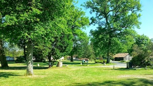 A park with trees, a picnic area, and a small building.