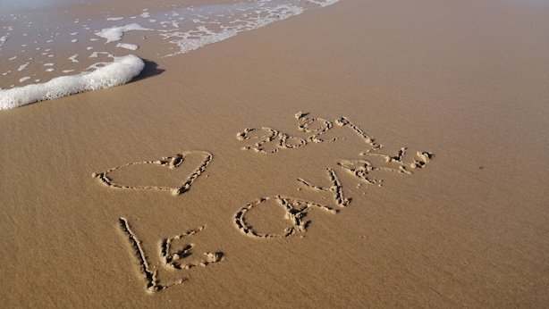 A beach with footprints spelling out "I love you" in the sand.