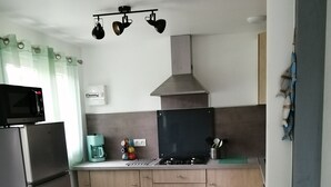 A modern kitchen with stainless steel appliances, a dining table with chairs, and a coffee maker.