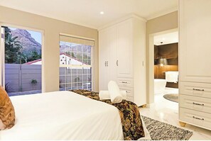 Relax in this serene bedroom with a large bed, wardrobe, and bathroom, offering a stunning mountain view.