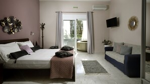 Une chambre d’hôtel avec un lit, un canapé, une télévision et une vue sur l’extérieur.