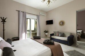 A bedroom with a bed, a sofa, a television, and a mirror.