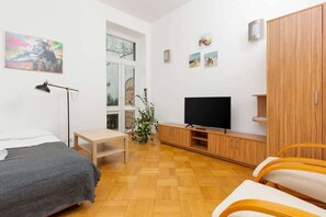 Quarto moderno com cama, escrivaninha, televisão e guarda-roupa.