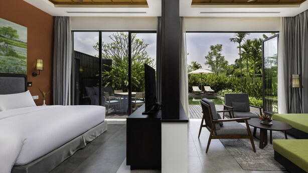 A modern hotel room with a large bed, a desk, and a seating area with a view of the garden and pool. - Angkor Green Gardens by Dara (Siem Reap)