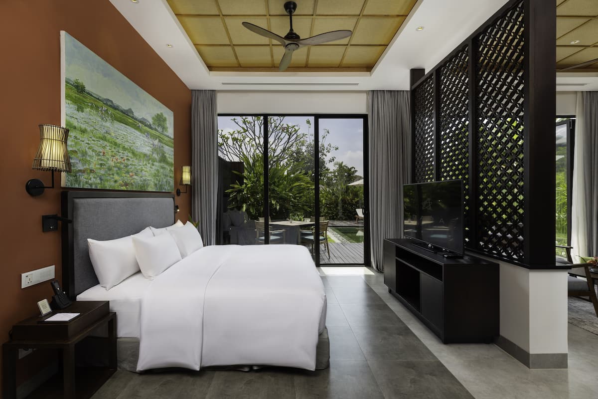 Een moderne hotelkamer met een groot bed, een flatscreen televisie, een plafondventilator en uitzicht op de omgeving.